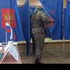 Un soldat rus cu mitralieră și cagulă e filmat când intră peste alegători în cabină, să verifice cum au votat la alegerile prezidențiale